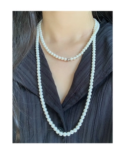 Detailed view of layered S925 silver pearl necklaces on a model with black fabric background