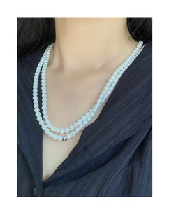 Double-layer pearl necklace with a silver ball accent worn on a black textured shirt