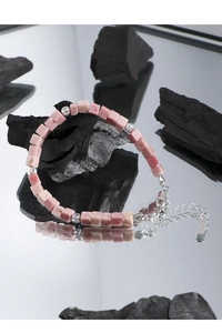 Detail view of S925 sterling silver beads and pink rhodonite stones on jewelry surface