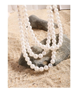 Detail of multi-layer white pearl necklace displayed on a natural rock by the beach