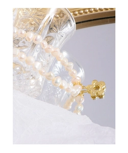 Detailed macro shot of baroque pearl necklace with a golden floral pendant and OT clasp
