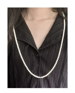 Detailed view of elegant S925 silver pearl necklace on black textured shirt
