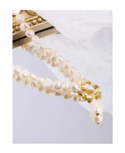 Macro shot of Baroque pearl necklace with gold OT clasp reflecting on a mirror surface