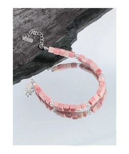 Macro shot of S925 silver clasp and pink rhodochrosite cube beads on stone surface