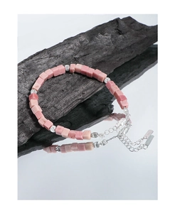 Detailed view of S925 silver tag and pink rhodochrosite beads on a minimalist bracelet