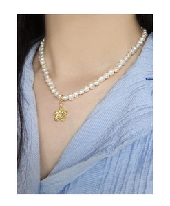 Close-up of S925 silver baroque pearl necklace with gold flower pendant on model
