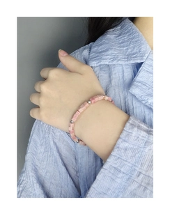 Detail of S925 silver bracelet with pink stone cubes on model's wrist and shoulder