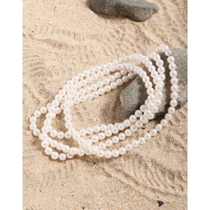 Elegant multi-layer pearl necklace on natural stones and sand background