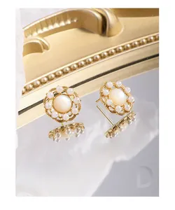 Détail macro des boucles d'oreilles fleur en argent S925 avec perle et finition or
