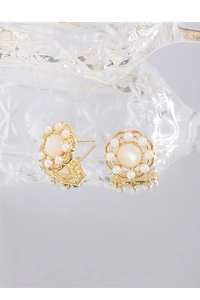 Détail de boucles d'oreilles fleurs dorées avec pierre centrale et petites perles