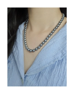 Detailed view of gray pearl necklace with high luster on a female model wearing a blue shirt