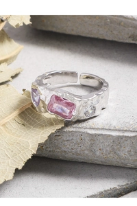 Macro shot of silver ring with textured metal, pink emerald cut and purple heart gems
