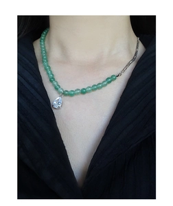 Macro view of water-drop green stone pendant and beaded silver chain on neck