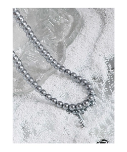 Detailed close-up of grey pearl necklace on a minimalist crystal glass background