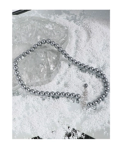 Close-up of gray pearl necklace with silver lobster clasp and extension chain on white ice