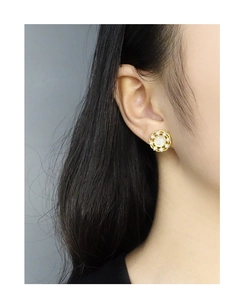 Gros plan d'une boucle d'oreille en perles et or de style vintage portée par un mannequin