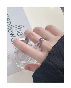 Close-up of S925 silver ring with pink and purple gemstones on hand with magazine