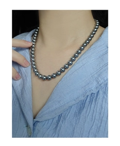 Detail view of a minimalist grey pearl necklace with metallic luster on a model