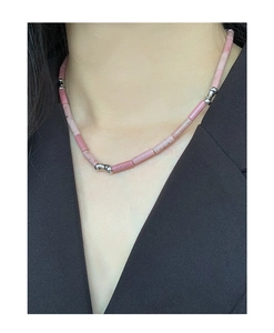 Detail shot of a S925 silver necklace with pink rhodochrosite beads on a black suit