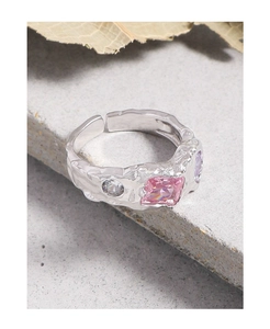 Macro shot of silver ring with irregular texture and inset colorful zircon stones