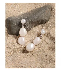 Detailed view of natural baroque pearl earrings with S925 sterling silver studs on sand