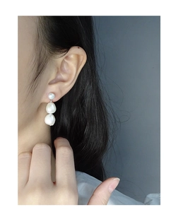 Detail view of a model wearing triple stacked white baroque pearl drop earrings