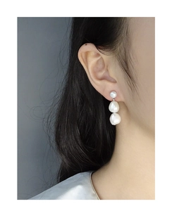 Detailed side view of a model wearing triple tiered baroque pearl earrings in S925 silver