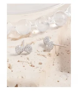 Macro detail of S925 sterling silver stamp on zircon bow earrings atop stone