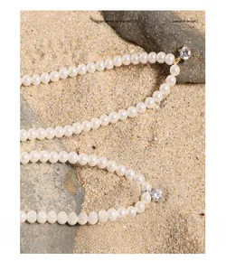 Macro detail of elegant pearl necklace with sparkling zircon pendant in natural sunlight