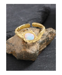Détail d'une bague dorée irrégulière avec pierre de lune sur un fond en pierre naturelle