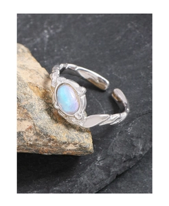 Vue macro d'une bague en argent S925 avec une pierre de lune bleue sur une surface rocheuse