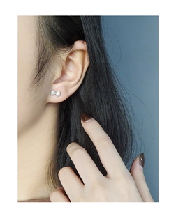 Close-up of S925 sterling silver bow knot earrings with sparkling cubic zirconia on ear
