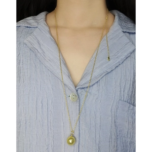 Collar largo minimalista de plata S925 con colgante de bola dorada en una camisa a rayas