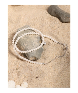 Close-up of double-layer pearl necklace with zircon pendant on a natural beach rock