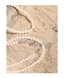 Detail of S925 silver pearl necklaces with zircon pendants on natural beach rocks