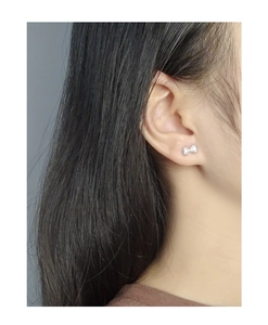 Close-up of bow knot stud earrings with cubic zirconia on a female model ear