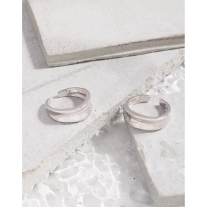 Minimalist S925 silver irregular wave open rings displayed on natural stones