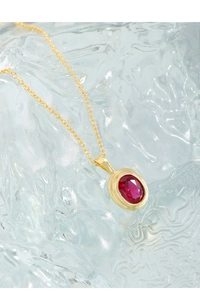 Macro shot of S925 silver necklace with red zircon pendant on water ripple glass
