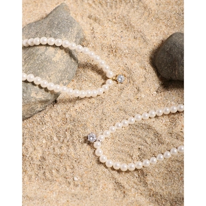 Minimalist S925 silver pearl necklaces with zircon pendants on natural sand background