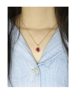 Close-up of red oval zircon pendant on a gold S925 silver chain worn by a model