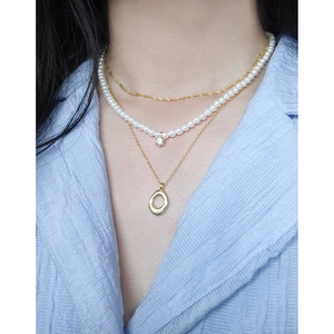 Three-layer layered necklace set with pearls, zircons and oval pendants on a model