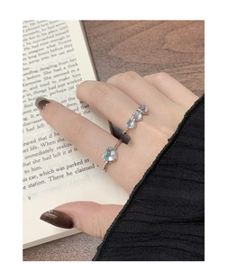 Detail of two S925 silver rings with heart moonstones worn by a model in a minimal setting