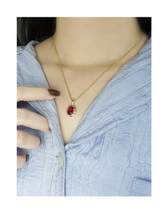 Close-up of S925 silver gold-plated necklace with oval red zircon pendant on a model