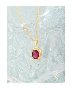 Macro view of oval red zircon pendant on a gold S925 silver chain with ice background