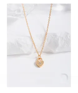 Détail d'un collier serrure coeur doré avec zircon sur un fond de style minimaliste