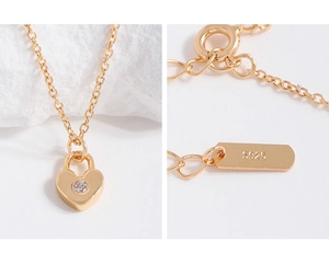 Gros plan du collier cadenas cœur doré montrant le poinçon S925 et le fermoir rond