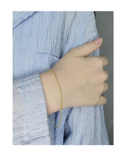 Gros plan d'un bracelet minimaliste en perles dorées porté sur un poignet élégant