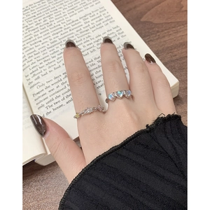Vintage silver heart moonstone ring set with colorful gemstone band on an open book