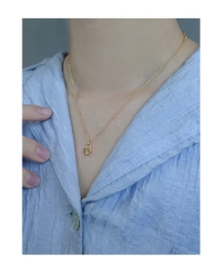 Détail d'un collier minimaliste en or avec pendentif cœur et zircon porté par un modèle