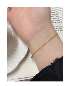 Gros plan détaillé d'un bracelet à perles dorées minimaliste porté au poignet